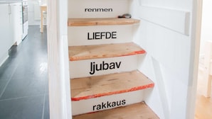 A staircase with wooden steps and white walls, leading to a kitchen area.
