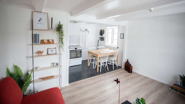 A spacious living area with a dining table, chairs, and a kitchen in the background.