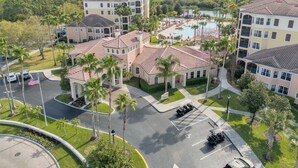 A multi-story hotel with a swimming pool, surrounded by palm trees and a parking lot. - Great View Condo, 2 Min. from Disney World!- 70 (Orlando)