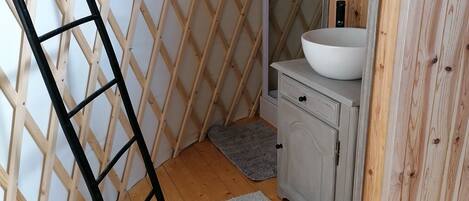 A corner bathroom with a wooden lattice wall, a white sink, and a small cabinet.