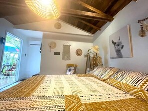 Un dormitorio con una cama grande, techo de madera, una ventana y una puerta que da a un balcón.