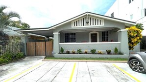A residential house with a front porch, a gated entrance, and a driveway with yellow lines. - 1920s Bungalow Studio w/ Courtyard Oasis (Miami)
