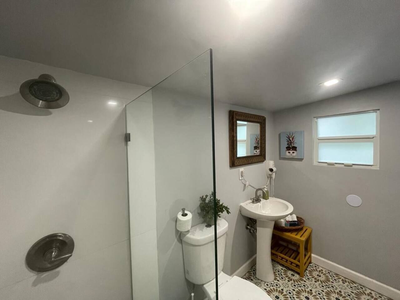A bathroom with a shower, toilet, sink, and a mirror.