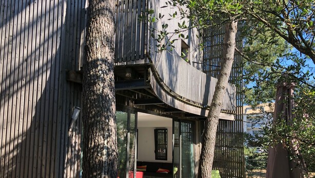 A modern outdoor seating area with a glass table and chairs, surrounded by trees and a wooden fence. - ECO-Responsible Treehouse / Welcome to Nature (Moliets-et-Maa)