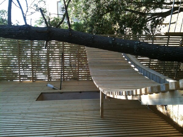 A wooden deck with a curved wooden structure, possibly a bench or seating area, surrounded by a wooden fence.