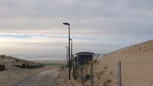 A pathway leading to a beach with a lifeguard tower and a fence. - ECO-Responsible Treehouse / Welcome to Nature (Moliets-et-Maa)