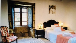A bedroom with a bed, a chair, a nightstand, a lamp, and a window.