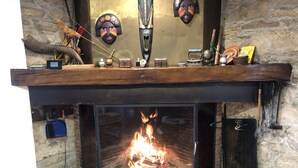 A fireplace with a fire, surrounded by stone walls and wooden beams.