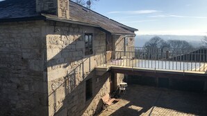 A stone building with a balcony overlooking a scenic view.