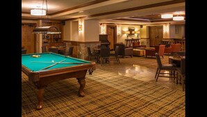 A pool table in a room with a patterned carpet, several chairs, and a bar area with a television. - SPRING BREAK Two-Bedroom Condo in Breck with private hot-tub! (Breckenridge)