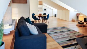 Un appartement moderne de style « loft », avec un coin repas, un canapé et une cuisine en arrière-plan.