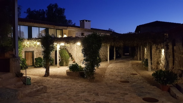 A stone courtyard with a rustic building, a wooden door, and potted plants.