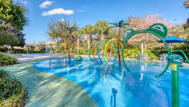 Un área de juegos con agua, con aros de colores y una decoración de tiburón verde.
