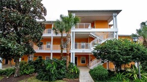 Un hotel de varios pisos con una escalera central, balcones y abundante vegetación.