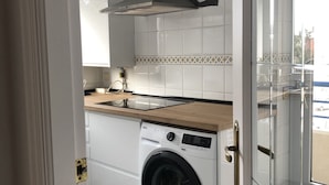 A compact kitchen with a built-in washing machine, a wooden countertop, and a modern backsplash. - Apt. on Mataleñas Beach next to the golf course and Playas del Sardinero (Santander)
