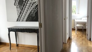 A hallway with a wooden floor, a white door, and a large black-and-white photograph of the Eiffel Tower. - Apt. on Mataleñas Beach next to the golf course and Playas del Sardinero (Santander)