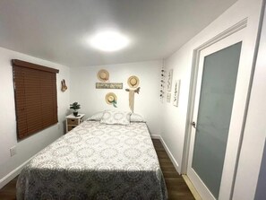 Une chambre à coucher avec un lit, une table de chevet, une plante en pot et une porte.