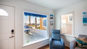 A room with a large window, a blue chair, and a view of the street outside. - Beach across the street, Alamitos Bay steps away! No hidden Fees! (Long Beach)