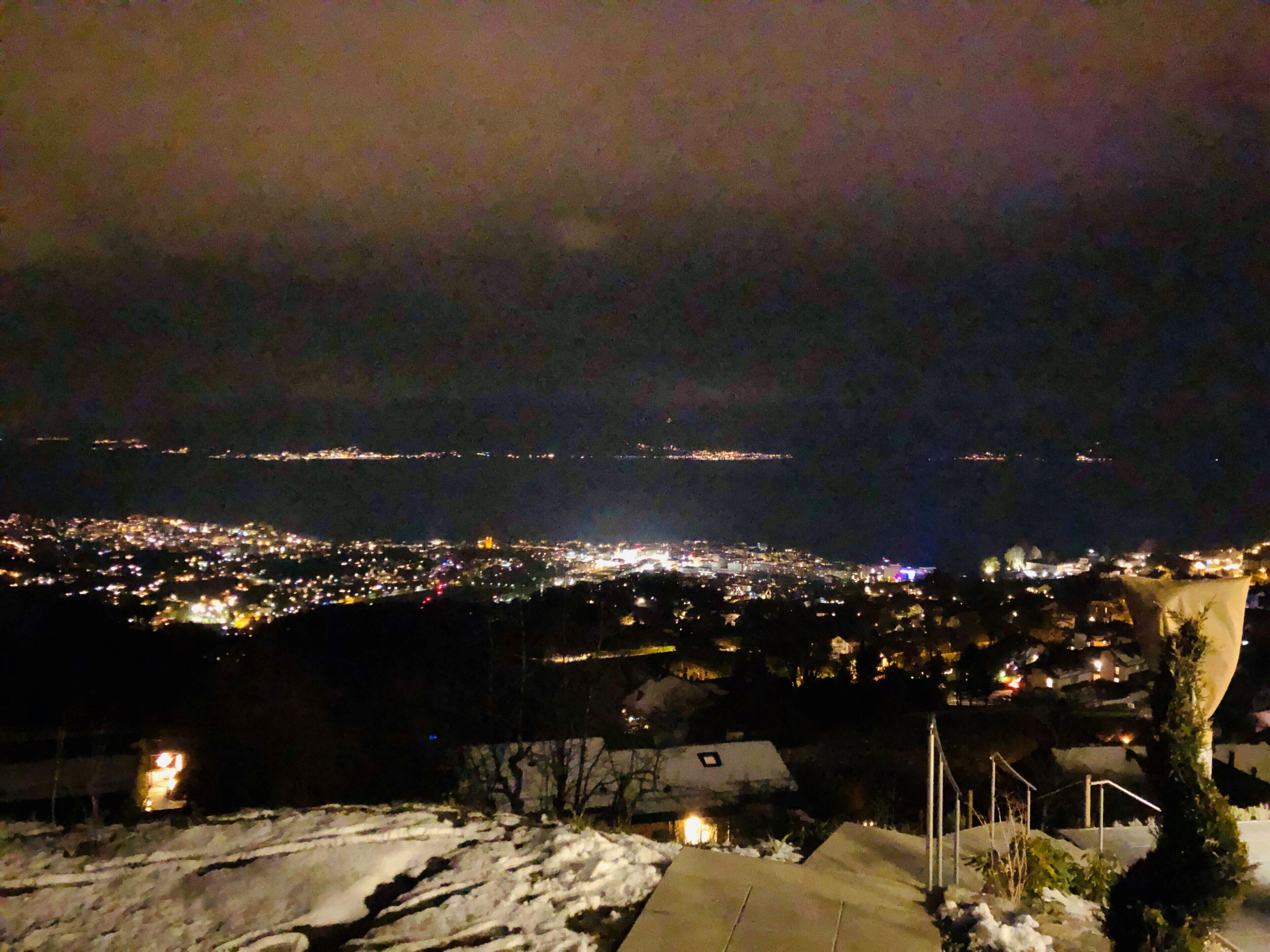 Ein nächtlicher Blick auf eine verschneite Stadtlandschaft mit weiter Stadtbeleuchtung.