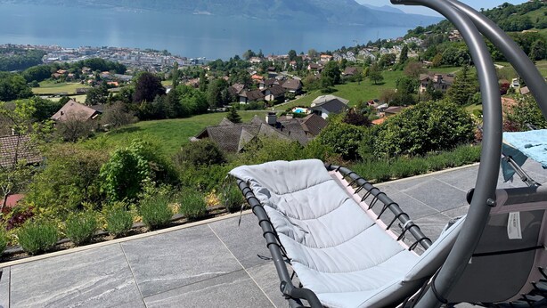 Ein Stuhl mit Blick auf einen See und Berge im Hintergrund.