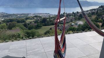 Una hamaca en un patio con baldosas con vistas a un lago y montañas.