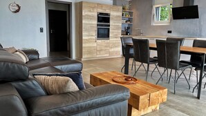 Ein modernes Wohnzimmer mit einer Ledersofa, einem Holztisch und einem Essbereich mit schwarzen Stühlen und einem Holztisch.