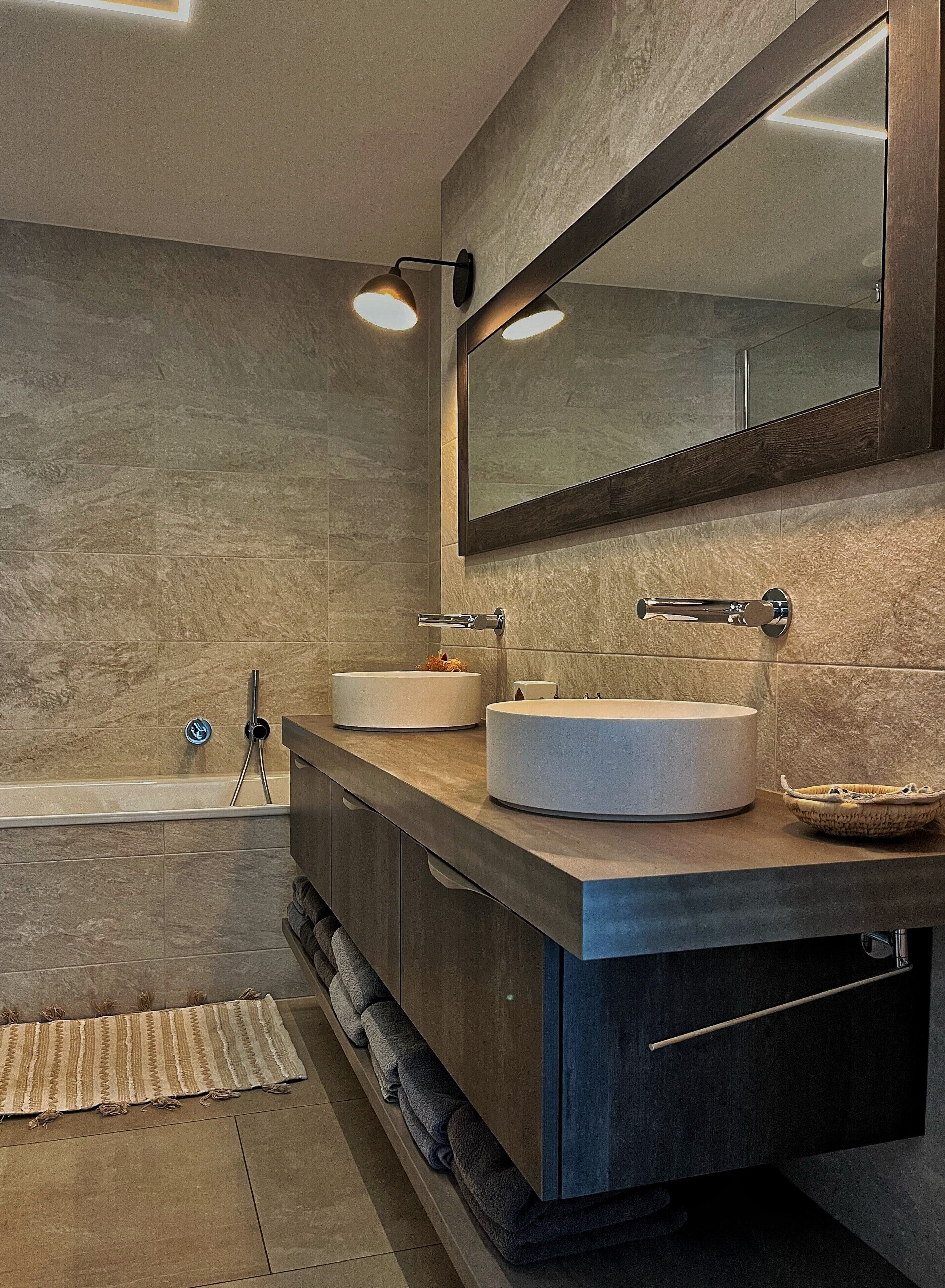 Un baño moderno con dos lavamanos, un espejo grande y una bañera.