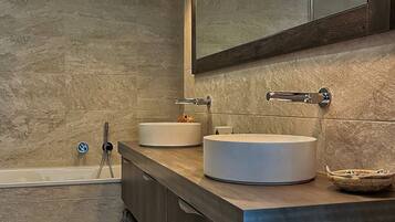Un baño moderno con dos lavamanos, un espejo grande y una bañera.