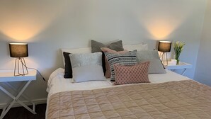 A neatly made bed with a quilted cover, multiple pillows, and two bedside lamps on white nightstands.