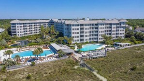 Un hotel de diverses plantes amb zona de piscina, gandules a l'aire lliure i un jardí paisatjístic.