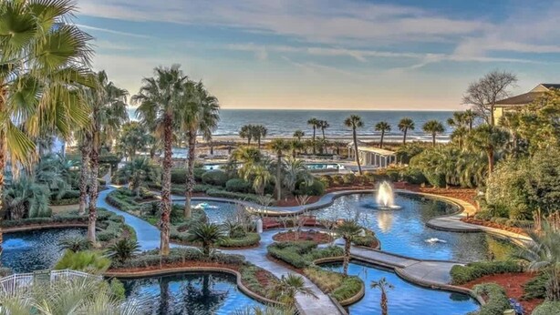 Un complex turístic amb diverses piscines, palmeres i vista a l'oceà.