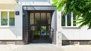 A building entrance with a gated door, a sign indicating room number 14, and a small window to the left. - Stylish Studio in Mokotow | Close to Metro and Parks (Warszawa)