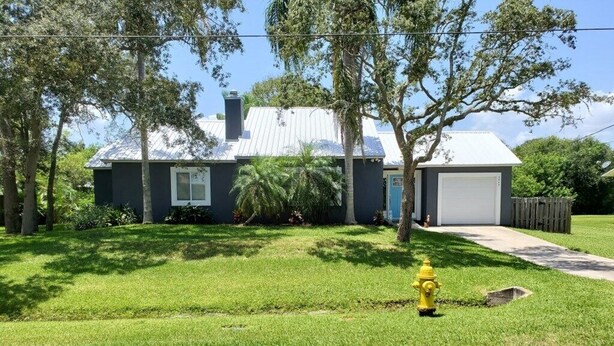 A residential house with a garage, a grassy yard, and a yellow fire hydrant.