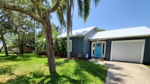 A residential house with a garage, a well-maintained lawn, and a large tree in the front yard. - Pet-Friendly 3BR Private Home with Pool Near Beach (St. Augustine)