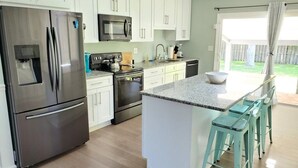 A modern kitchen with white cabinets, stainless steel appliances, and a central island with bar stools.