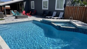 A swimming pool with clear blue water, surrounded by lounge chairs and a wooden fence. - Pet-Friendly 3BR Private Home with Pool Near Beach (St. Augustine)