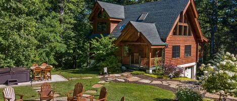 A log cabin with a porch, outdoor seating, and a fire pit.
