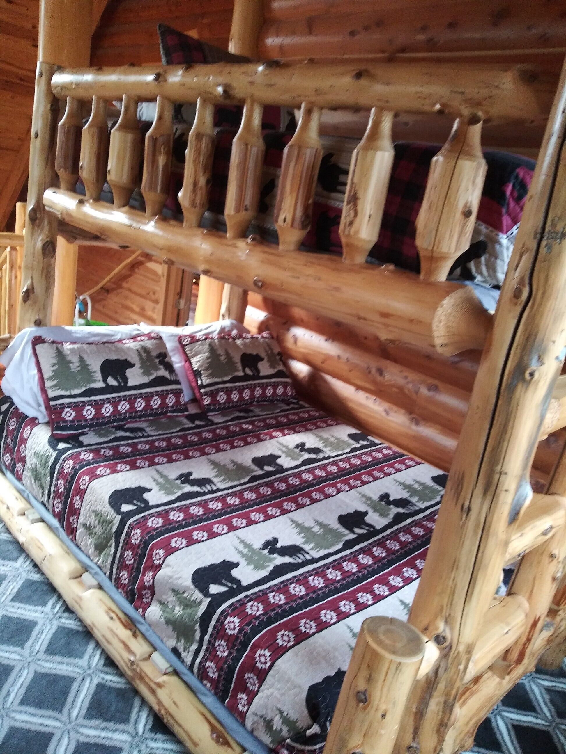 A wooden bunk bed with a patterned blanket and pillows.