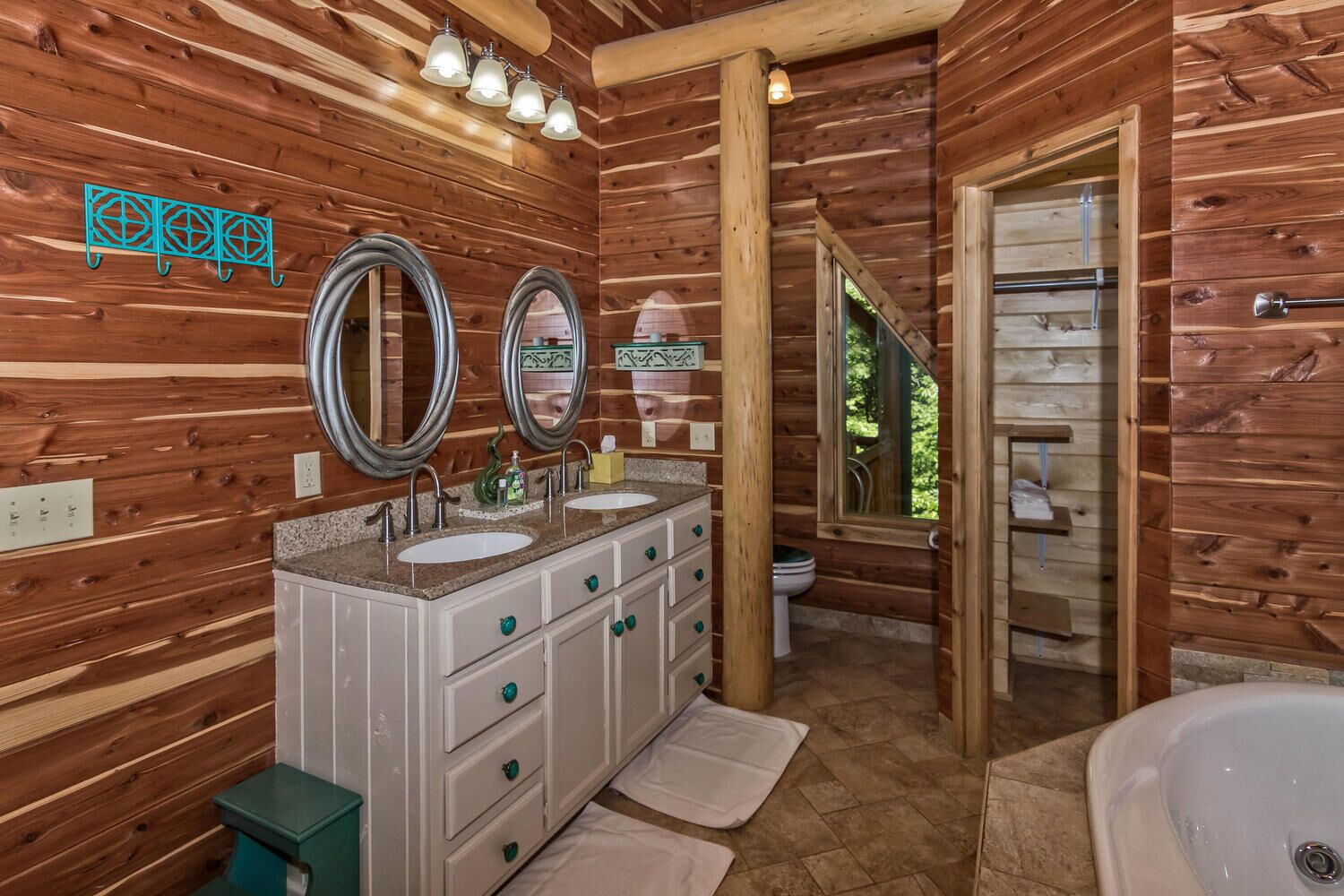 A wooden cabin bathroom with two sinks, a large mirror, and a bathtub.