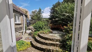 Een stenen trap leidt naar een tuin met uitzicht op een stenen gebouw en bomen.