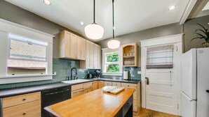 A modern kitchen with wooden cabinets, a central island, and pendant lighting. - The Proctor House: North End, Old Town, Ruston (Tacoma)