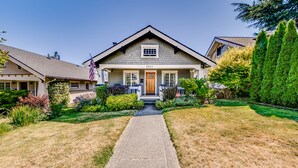 A two-story house with a front porch, a driveway, and well-maintained landscaping. - The Proctor House: North End, Old Town, Ruston (Tacoma)