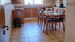 A kitchen with wooden cabinets, a dining table with chairs, and a window providing natural light. - Violante Apartment Beach (Foz do Arelho)