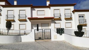 A white building with red-tiled roofs, multiple balconies, and a gated entrance. - Violante Apartment Beach (Foz do Arelho)
