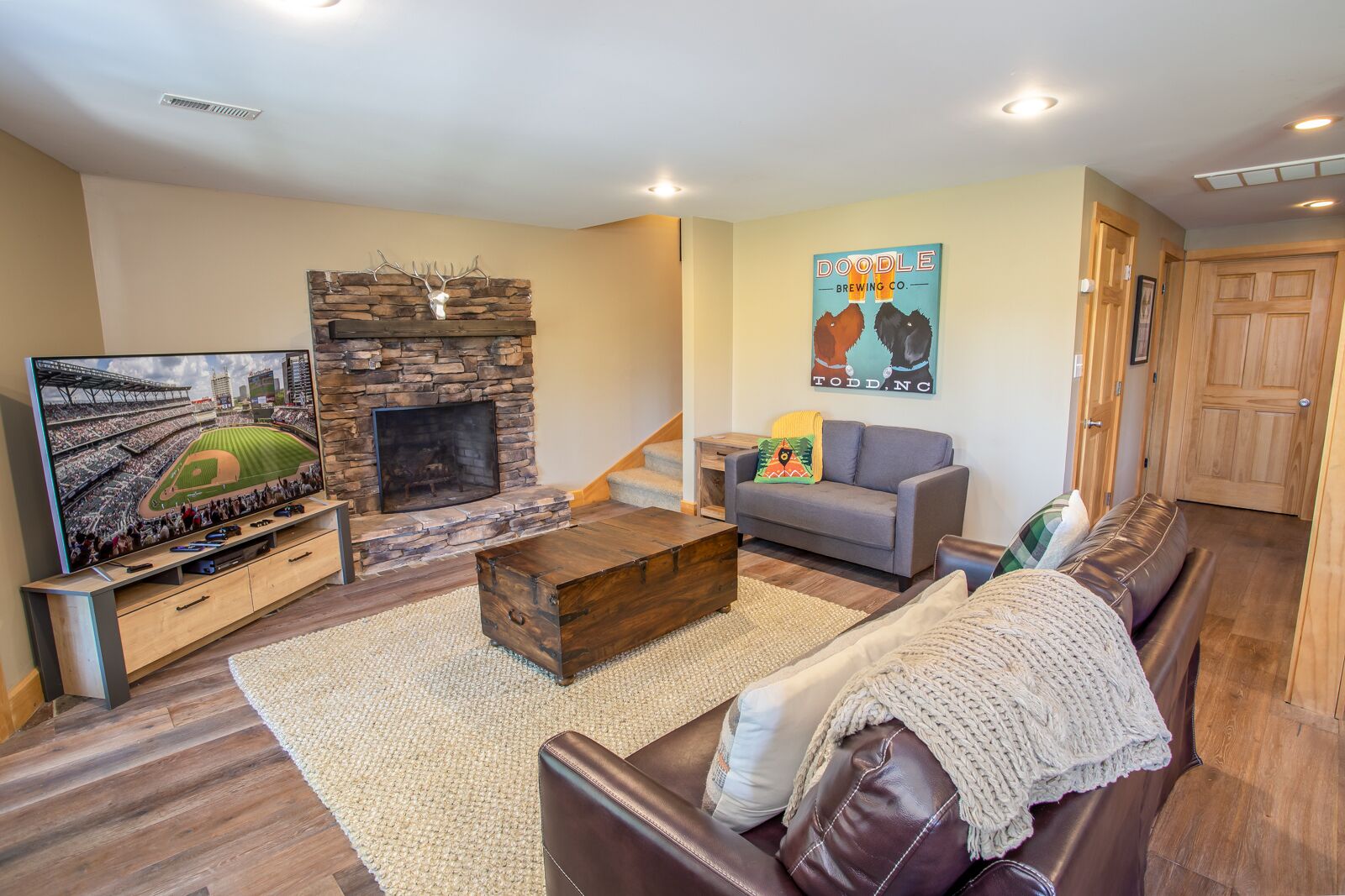 A living room with a stone fireplace, a television, a sofa, and a couch.