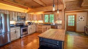 Une cuisine spacieuse dotée de meubles en bois, d’appareils électroménagers en acier inoxydable et d’un grand îlot central.