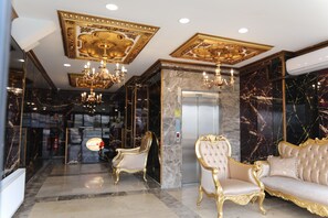 A luxurious lobby with ornate chandeliers, marble flooring, and classic gold-accented furniture.
