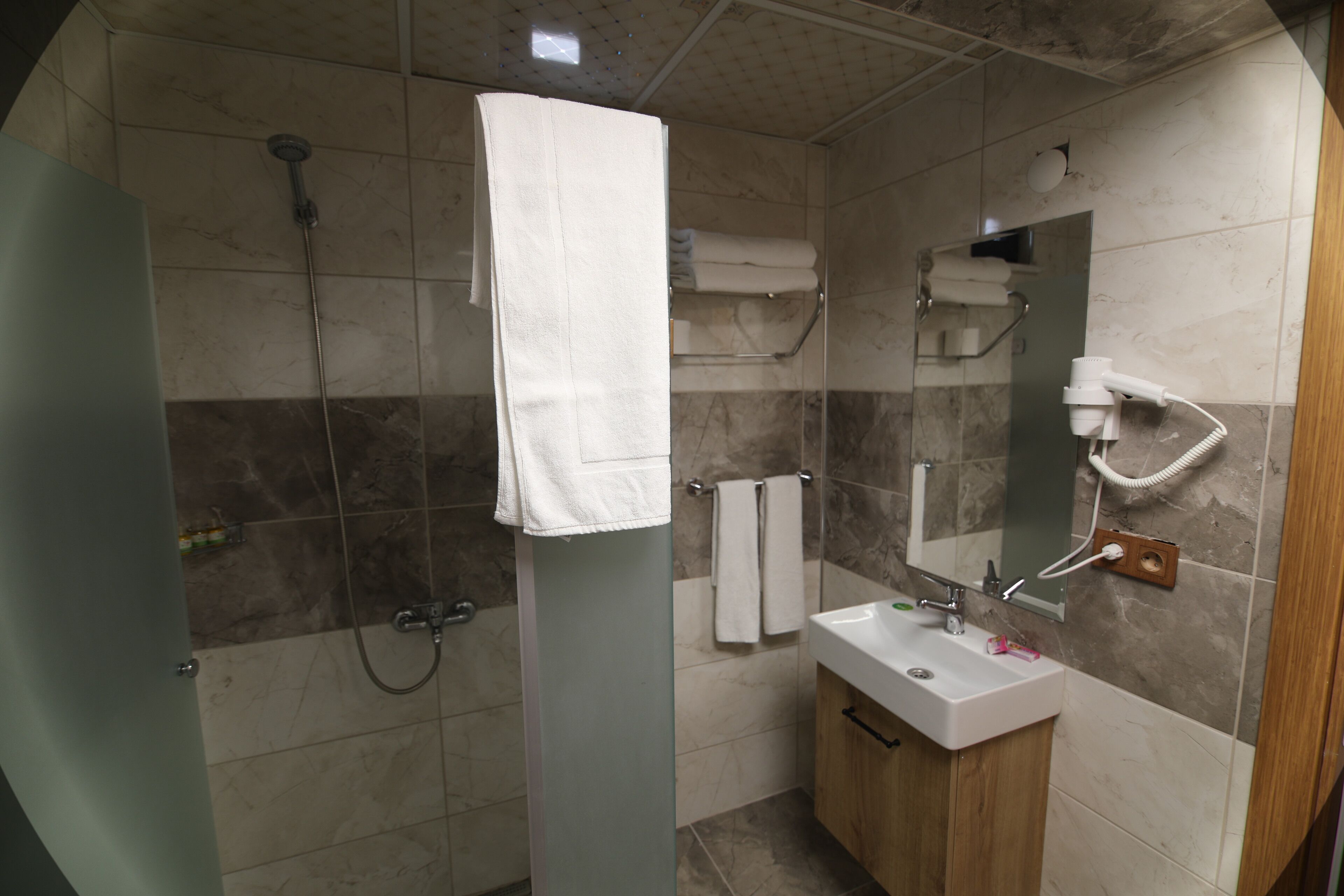 A modern bathroom with a glass shower enclosure, a sink, and a mirror.