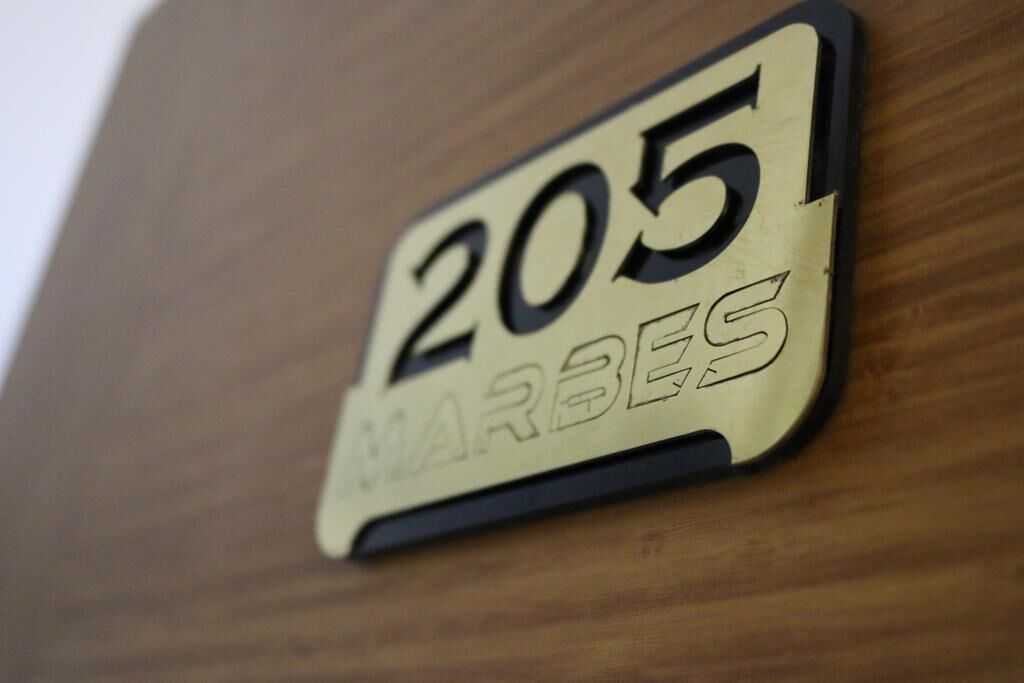 Un letrero con el número 205 y la palabra 'MARBES' sobre una superficie de madera.