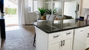 A kitchen with white cabinets, a black countertop, and a window with white curtains. - Newly Renovated St. George Getaway!! (St. George)